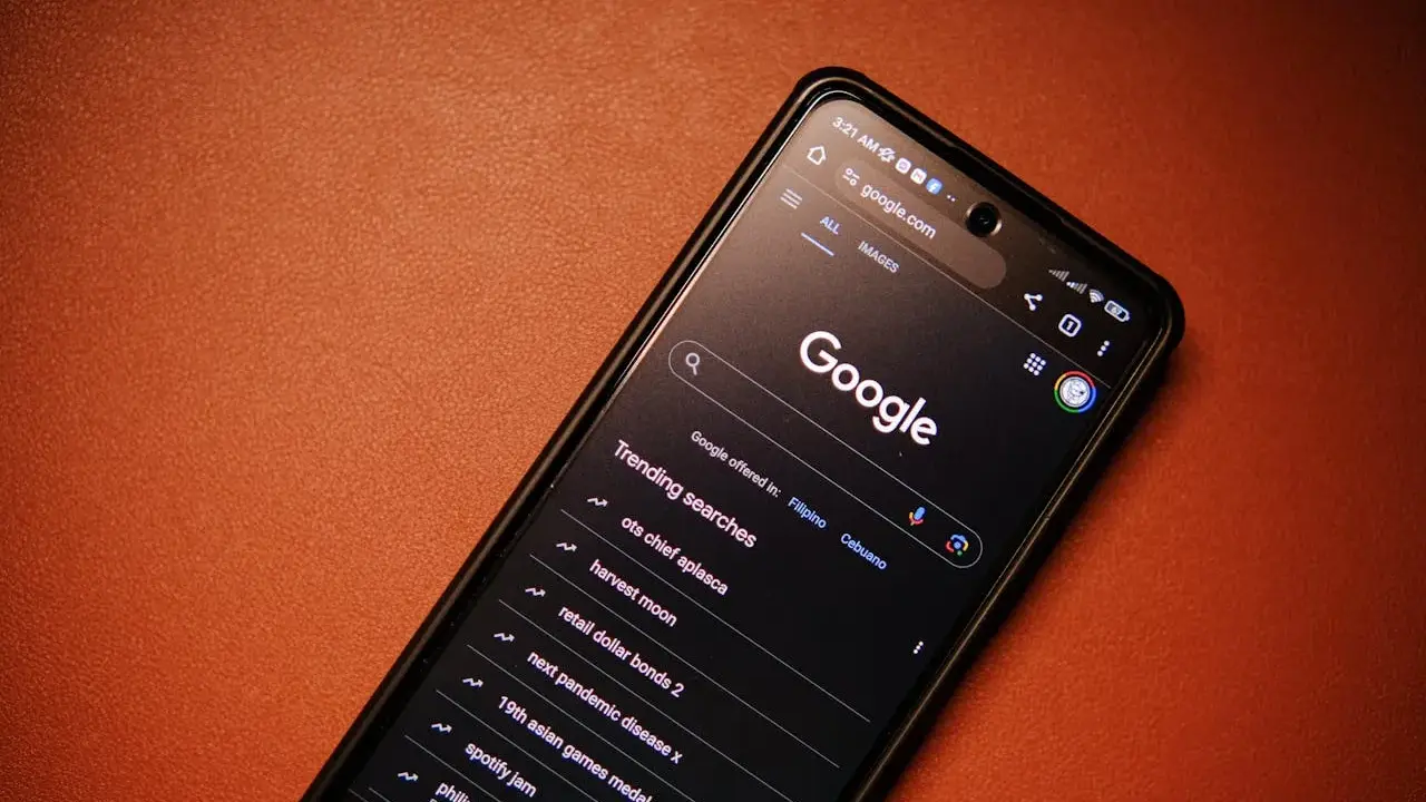 Smartfon z włączoną wyszukiwarką Google i listą popularnych wyszukiwań.