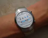 Zegarek na ręce z cyfrowym wyświetlaczem w stylu binarnym.