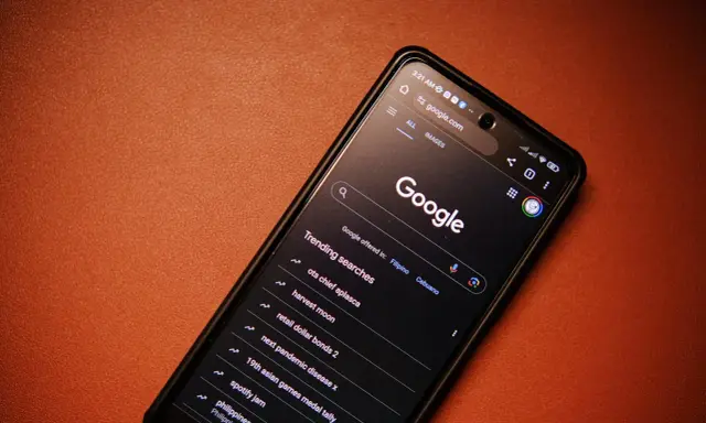 Smartfon z włączoną wyszukiwarką Google i listą popularnych wyszukiwań.