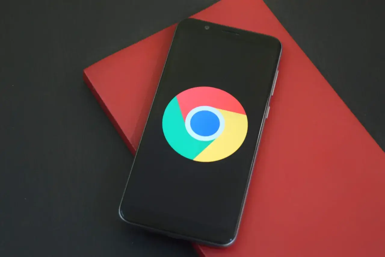 Smartfon z logo Chrome. Dowiedz się, jak wyczyścić historię przeglądarki, aby zachować prywatność.